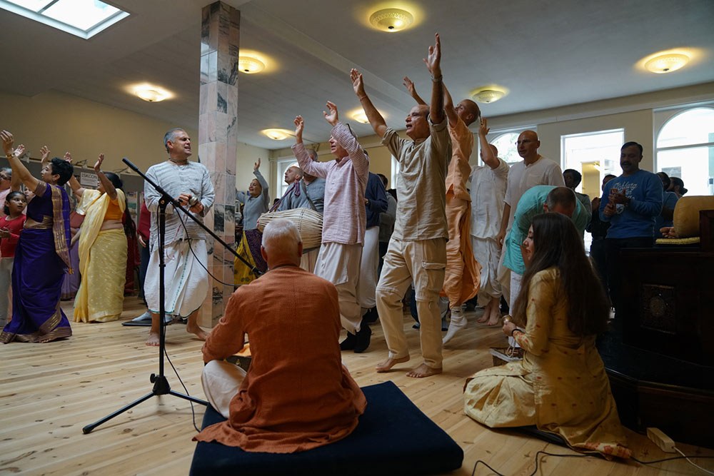 Devotees and guests singing and dancing in kirtan in the temple hall